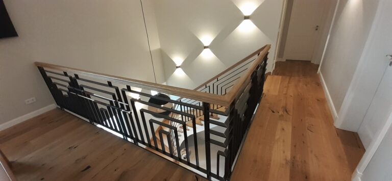 Galeriegeländer aus schwarzem Metall mit geometrischem Muster und Holzhandlauf