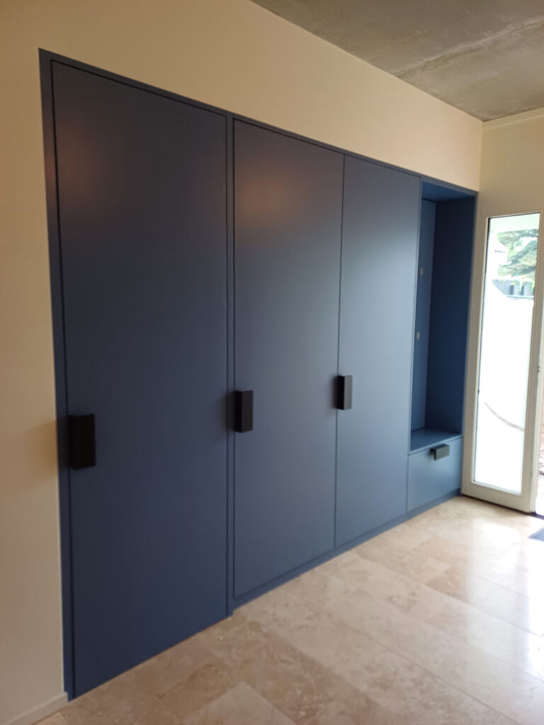 Raumhohe Einbaugarderobe in Blaugrau mit integrierter Sitznische im Eingangsbereich