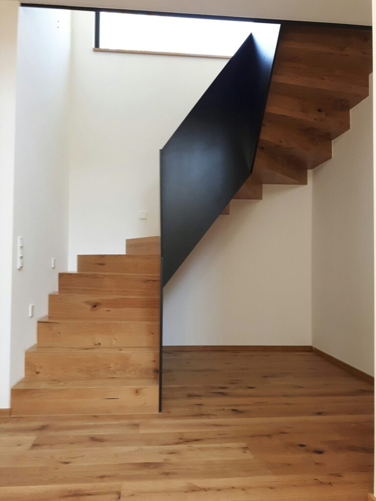 Gewendelte Faltwerktreppe aus Eiche mit geschlossener schwarzer Stahlbrüstung
