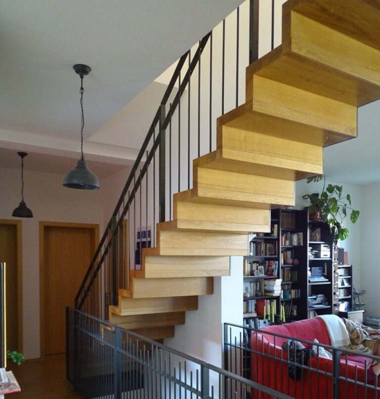 Faltwerktreppe aus hellem Holz, frei im Raum stehend, mit schwarzem Stabgeländer