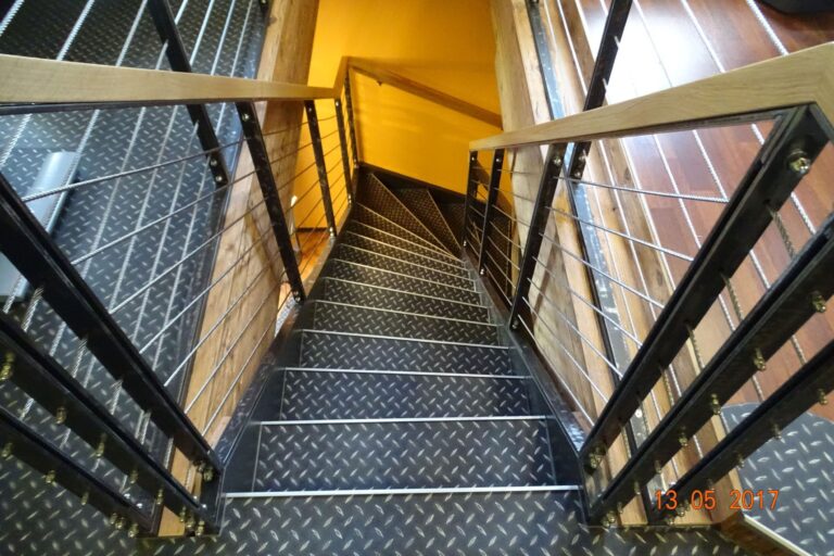 Blick von oben auf eine Stahltreppe mit Riffelblechstufen und Zwischenpodest