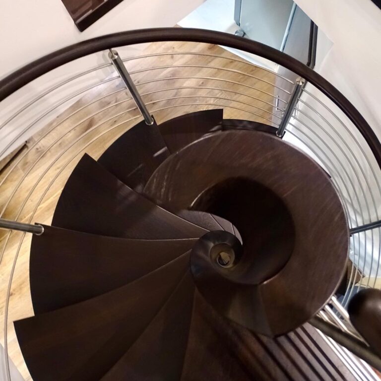Blick von oben auf eine Spindeltreppe: dunkle Stufen laufen keilförmig auf die Mittelsäule zu