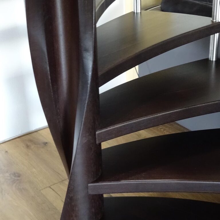 Detailaufnahme der gewendelten Außenwange einer Spindeltreppe aus dunklem Holz